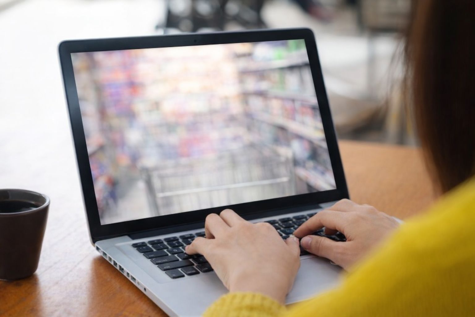 En person i gul tröja skriver på en bärbar dator för att hitta rabatter.