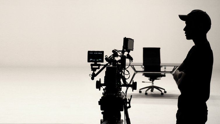 Silhuett av en filmkamera och en person i en professionell studio.